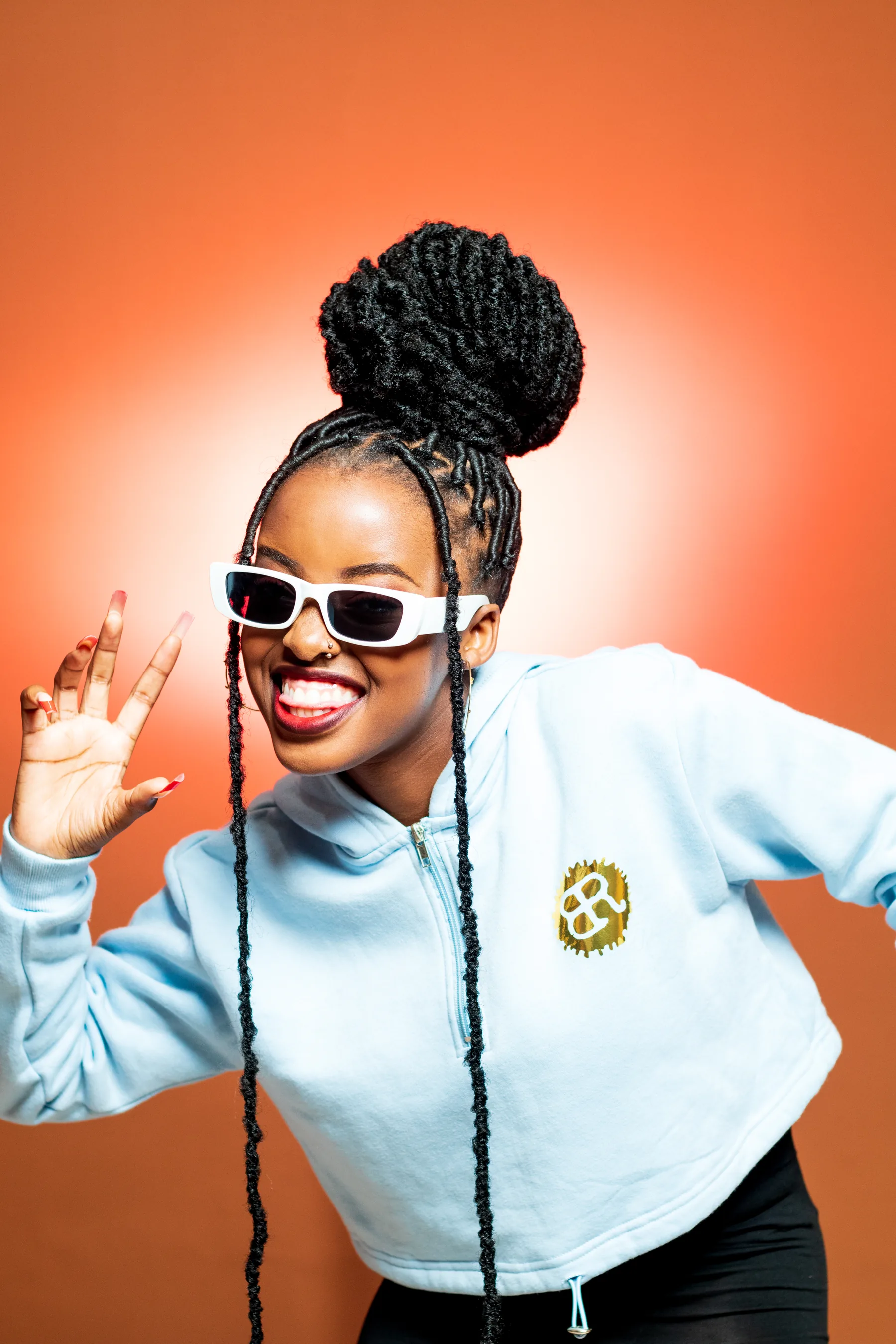 Rebellious Threads Africa streetwear campaign — model in a pale blue cropped hoodie on an orange backdrop, Johannesburg